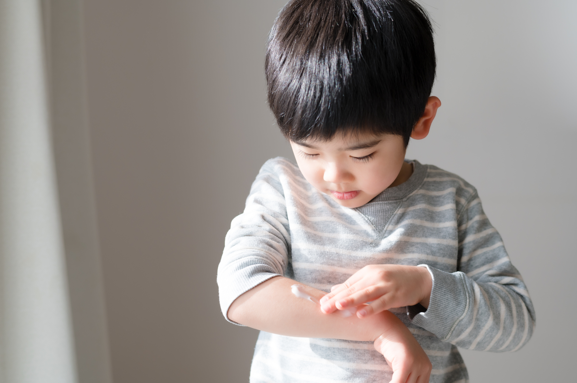 腕にクリームを塗っている子ども